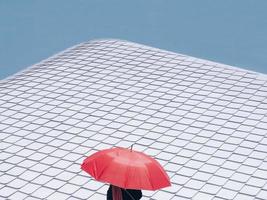 Ein roter Regenschirm vor einem weißen Stahlschindeldach in der Stadt foto