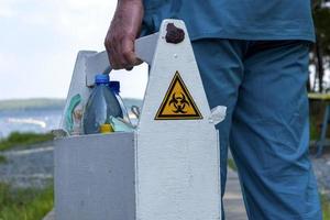 biohazard-schild auf der box mit wasserproben aus dem see in den händen eines mitarbeiters foto