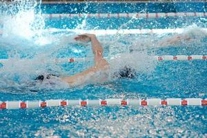 ein beanie-schwimmer streckt seine arme während eines brustschwimmtrainings im pool aus, unscharfer fokus foto