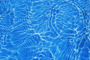 defocus verschwommene, transparente, blaue, klare, ruhige wasseroberflächenstruktur mit spritzer, blase. glänzender blauer wasserkräuselungshintergrund. Wasseroberfläche im Schwimmbad. blaues Blasenwasser scheint. foto
