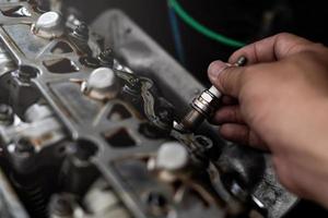 Alte Auto-Zündkerze in der Hand des Technikers Entfernen und Ändern des Servicekonzepts für den Hintergrund des Maschinenraums foto