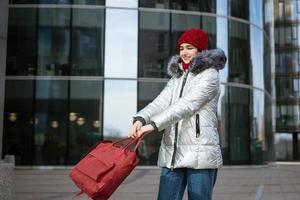 junge glückliche Frau in einer warmen Jacke mit Rucksack reist durch die Städte foto