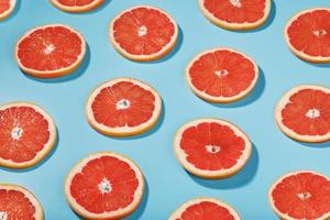 Muster von Scheiben saftiger Grapefruit auf blauem Hintergrund, ein schönes Muster. foto