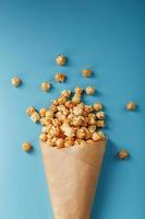 Popcorn in Karamellglasur in einem Papierumschlag auf blauem Hintergrund. foto