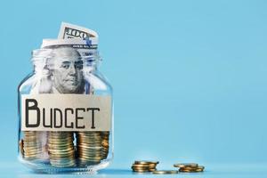 Ein Glas mit Münzen und der Aufschrift Budget auf blauem Hintergrund. foto