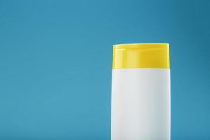 weiße Plastikflasche mit gelber Kappe mit Shampoo-Gel auf blauem Hintergrund. foto