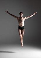 der junge attraktive moderne Balletttänzer, der auf weißem Hintergrund springt foto