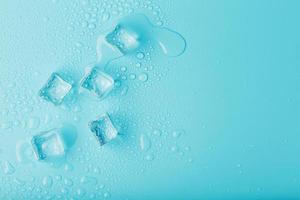 Eiswürfel mit Wassertropfen auf blauem Hintergrund verstreut, Ansicht von oben. foto