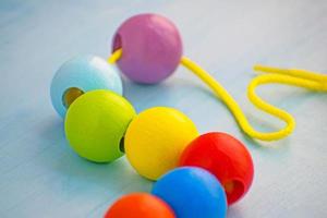 Entwicklungsspielzeug für Kinder. farbige Holzkugeln an einem Seil. bunte hölzerne Babyperlen für Halskette. foto