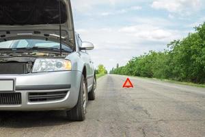 Auto mit Problemen und ein rotes Dreieck, um andere Verkehrsteilnehmer zu warnen foto