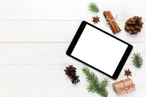 digitales tablet-modell mit rustikalen weihnachtlichen hölzernen hintergrunddekorationen für app-präsentation. draufsicht mit kopierraum foto