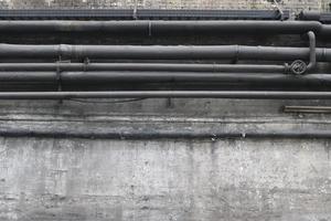 Wand in einem Stahlwerk mit deutlichen Gebrauchsspuren, Rissen und Rohren. Hintergrund mit hoher Auflösung. foto