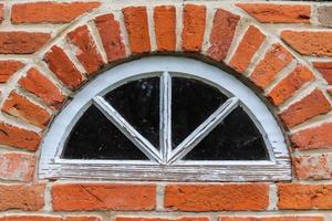 alte Backsteinmauer. Textur der alten verwitterten Ziegelwand mit einem runden Fenster. foto