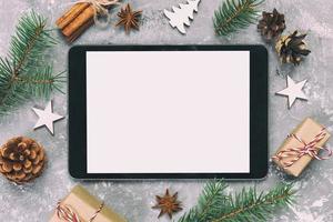 digitales tablet-modell mit rustikalen weihnachtlichen grauen zementhintergrunddekorationen für die app-präsentation. draufsicht mit kopierraum. getönt foto