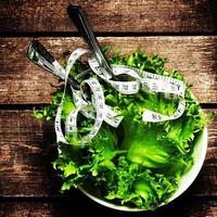 Salat mit Fitnessmaßband über Holzhintergrund foto