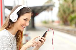 jugendlich Mädchen, das die Musik mit Kopfhörern wartet Zug hört foto