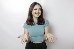 Junge asiatische Frau mit blauem Hemd, die eine Idee präsentiert, während sie auf isoliertem weißem Hintergrund lächelt foto
