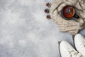 Winterurlaubskonzept. skates warme kleidung, tasse heißen tee mit duftenden gewürzen auf grauem hintergrund. Platz kopieren foto