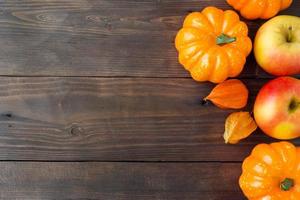 herbstkonzept, hölzerner hintergrund gelbe helle kürbisäpfel und physalis. Platz kopieren foto