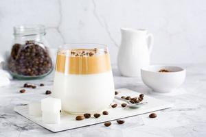 Dalgona-Kaffee in einem Glas und Zutaten zum Kochen auf dem Tisch. Social-Media-Trendgetränk. foto