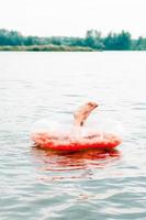 Kinderbeine ragen aus einem aufblasbaren Ring im Fluss. lokaler Tourismus. Sommerurlaub foto