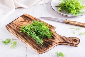 ein Bund Dill auf einem Schneidebrett auf dem Tisch. Bio-Naturgewürz. foto