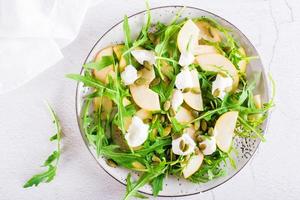 Birnensalat mit Rucola, Käse und Kürbiskernen auf einem Teller. hausgemachtes Mittagessen. Ansicht von oben. Nahansicht foto