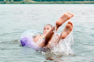 Das Mädchen kneift sich in die Nase und fällt aus dem aufblasbaren Ring in den Fluss. lokaler Tourismus. foto