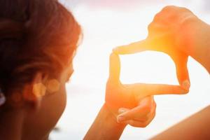 Hand, die weit entfernten Blick über den Sonnenuntergang einrahmt foto