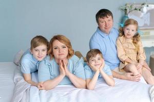 glückliche familie, die auf ihrem bett im schlafzimmer in die kamera schaut. kaukasische Eltern foto