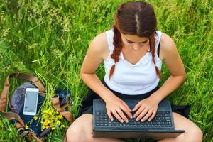 Student sitzt mit einem Laptop auf dem Rasen, Ansicht von oben foto