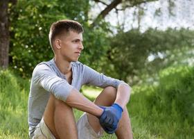 junger Mann ruht sich nach der Reinigung des Parks aus foto