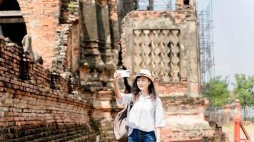 junge hipster-frau, die auf ihrer handykamera eine wunderschöne landschaft fotografiert, während sie während einer erstaunlichen reise in der nähe des tempels steht foto