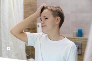 Ein hübscher Teenager genießt sein Spiegelbild allein im Badezimmer foto