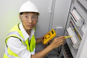 männlicher ingenieur, der elektrisches system mit elektronischen geräten überprüft foto