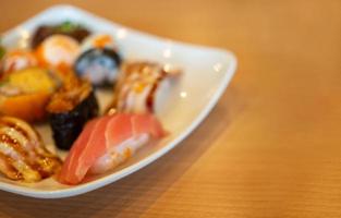 Verschiedene Sushi in einem weißen Teller auf einem Holztisch foto