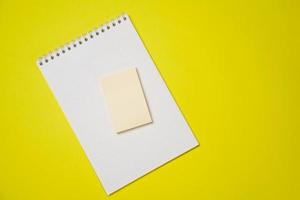 Öffnen Sie einen leeren weißen Notizblock auf einer Spirale und Aufkleber auf gelbem Hintergrund. foto