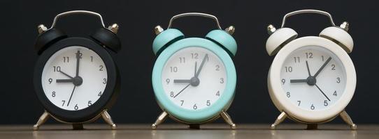 drei kleine wecker schwarz blau und weiß zeigen neun uhr, stehen foto