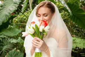 Porträt der schönen Braut, die Brautstrauß riecht foto