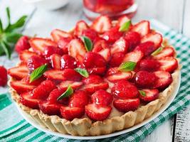 Torte mit Erdbeeren und Schlagsahne, dekoriert mit Minzblättern foto
