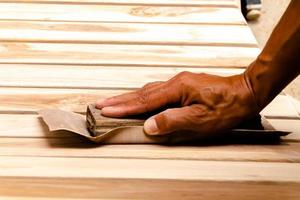 Arbeiten, um Holz zu glätten und mit Schleifpapier zu reinigen foto