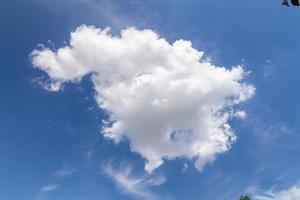 weiße Wolken, die schweben und sich mit einem blauen Himmel im Hintergrund bilden foto