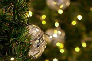 Kristallkugel auf Kiefer am Weihnachtstag mit verschwommenem Hintergrund und Bokeh der Weihnachtsbeleuchtung dekoriert.