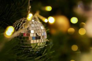 Kristallkugel auf Kiefer am Weihnachtstag mit verschwommenem Hintergrund und Bokeh der Weihnachtsbeleuchtung dekoriert.