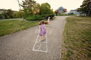 Zwei Schwestern, die im Park Himmel und Hölle spielen. Kinderspiel, Outdoor-Aktivitäten für Kinder. foto