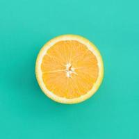 Draufsicht auf eine orangefarbene Fruchtscheibe auf hellem Hintergrund in türkisgrüner Farbe. ein gesättigtes Zitrustexturbild foto