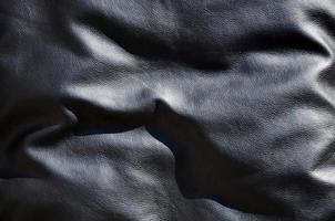 Textur aus schwarzem Leder oder Dermantin mit Falten, verwendet als Material für Damen- und Herrentaschen, Koffer, Kissen für Bürosofas und auch für Polstermöbel foto