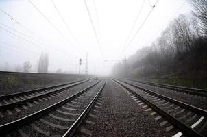 die Bahngleise an einem nebligen Morgen. viele schienen und schwellen gehen in den nebligen horizont. Fisheye-Foto mit erhöhter Verzerrung foto