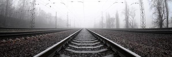 die Bahngleise an einem nebligen Morgen. viele schienen und schwellen gehen in den nebligen horizont. Fisheye-Foto mit erhöhter Verzerrung foto