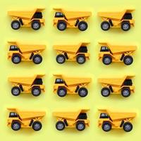 viele kleine gelbe spielzeuglastwagen auf texturhintergrund aus modepastellgelbem farbpapier in minimalem konzept foto